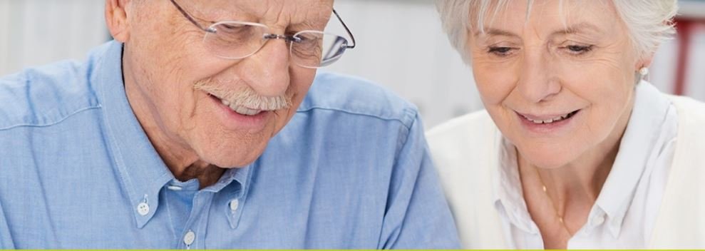 Oudere man en vrouw kijken samen glimlachend naar een tablet